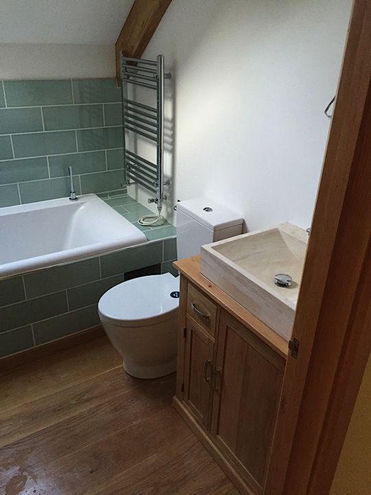 Bathroom with green tiles and a wooden vanity