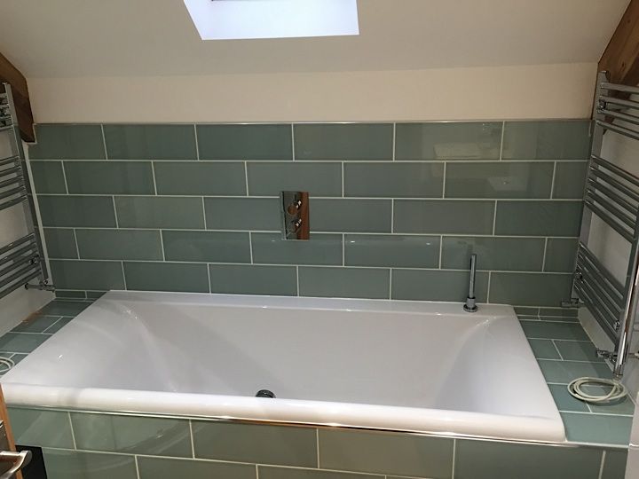 Bath in a bathroom with green tiles